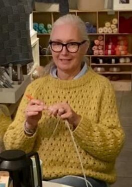 Kvinde i gul sweater som strikker